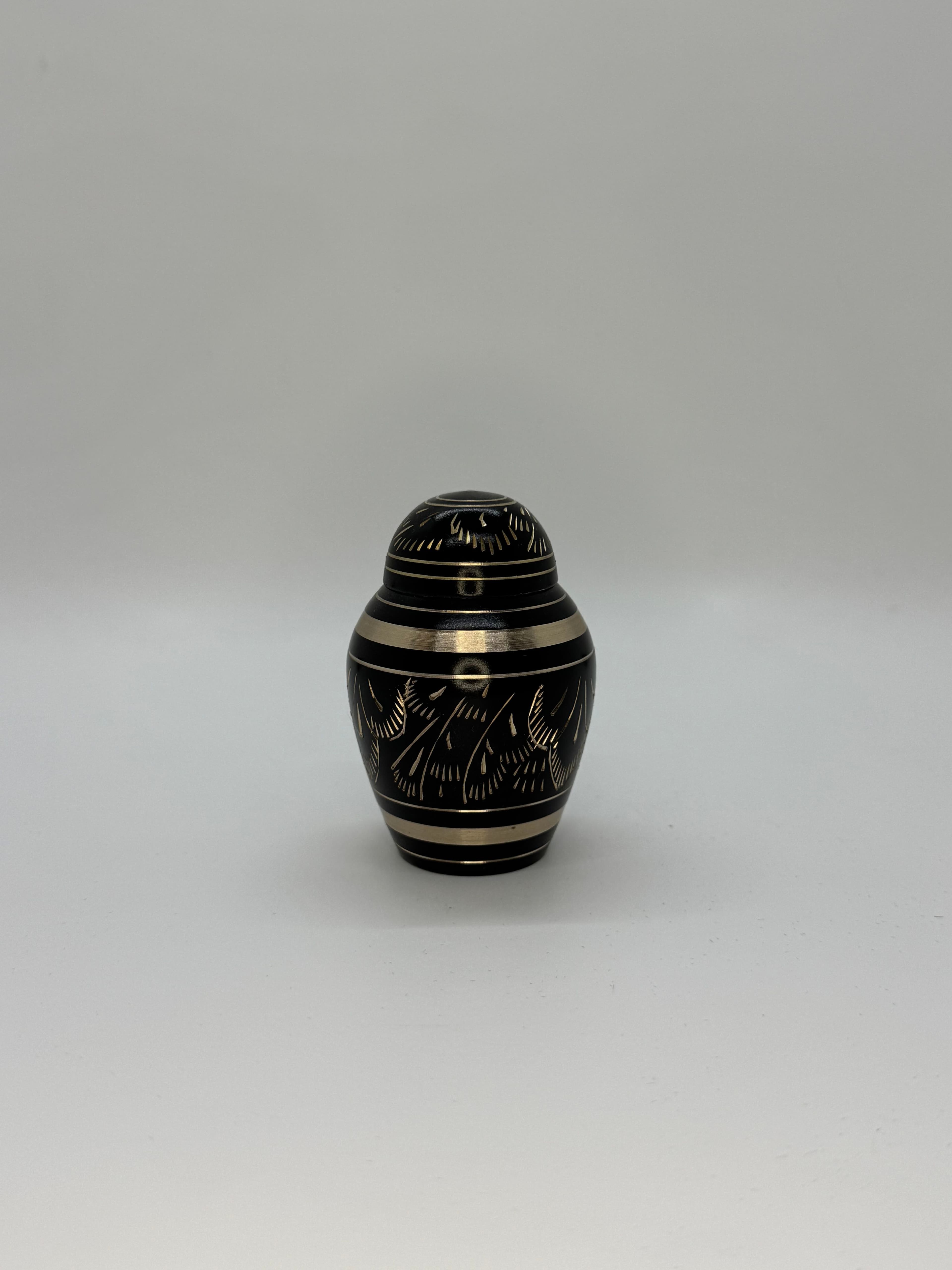 Black metal keepsake urn with gold color engraved embellishments.